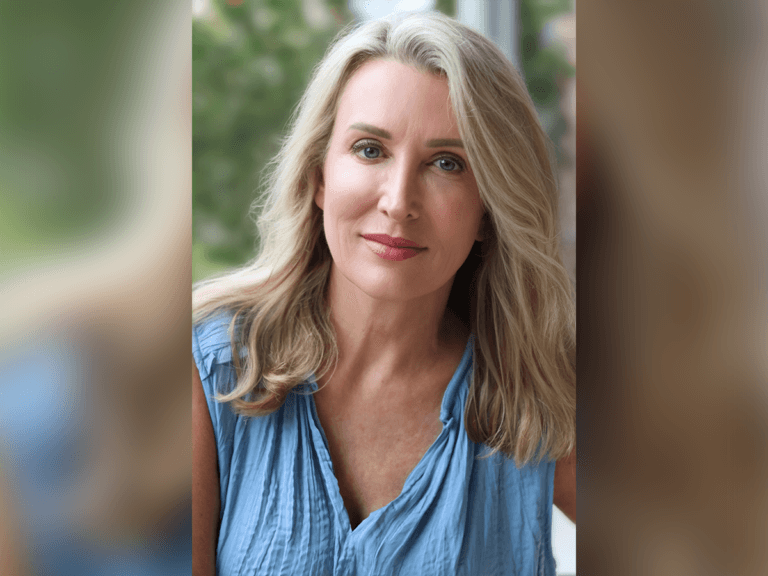 Actor Amy McKillop smiling outside in a blue shirt.